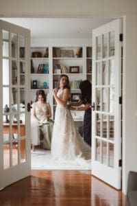 bride getting ready with the help from mom and maid of honor