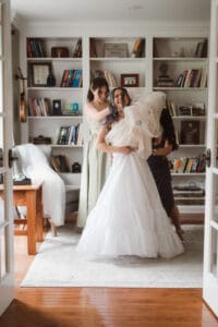 bride getting ready with the help from mom and maid of honor