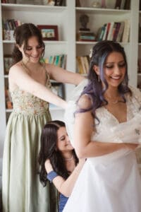 bride getting ready with the help from mom and maid of honor